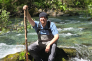 Veteran Colton Long sits on a rock amidst a bubbling stream. 