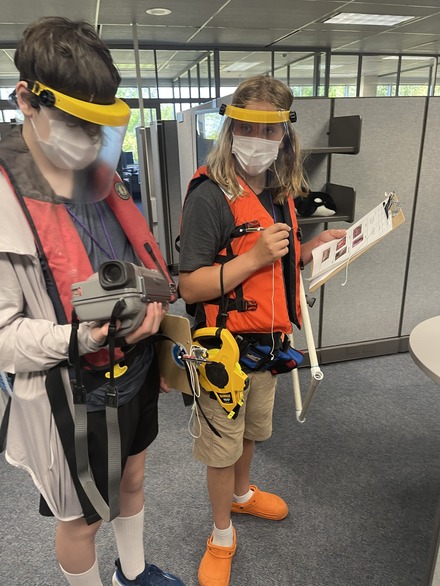 Students participate in a “rockfish survey” at NOAA Science Camp, carrying and wearing a variety of mock scuba gear.