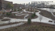 Construction of a riverfront park is shown from an aerial view.