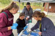 Lower Elwha Klallam tribal members talk with a NOAA Outreach and Engagement Specialist under a pop-up tent 