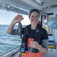 woman on deck holding fish still on hook and line gear