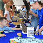  A scientist standing in front of an outreach booth looking at a little boy. 