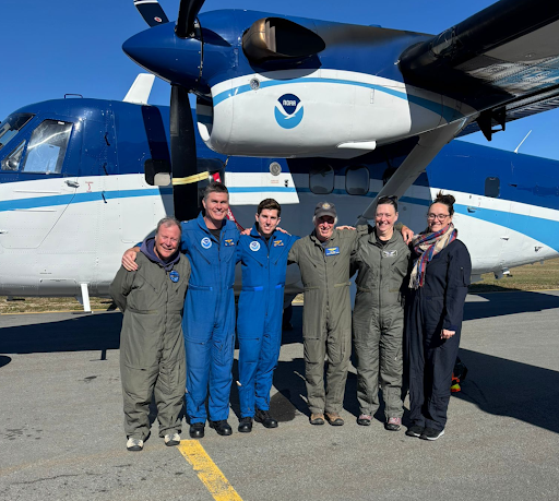 Six aerial survey scientists and aircraft crew pose in front of a Twin Otter aircraft.