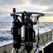 Water and oceanographic sampling gear on the side deck of a research vessel at sea.