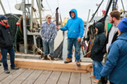 Captains talk with Cooperative Research Summit participants during the Shinnecock port tour at the commercial fishing dock learning stations.