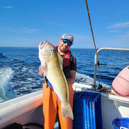 Man holds large golden tilefish on stern of boat