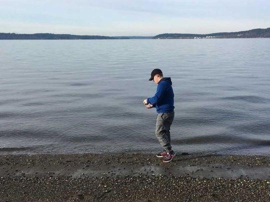 Volunteer collects microplastics from beach.