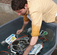 high school male student tests his robotic vehicle in a tub