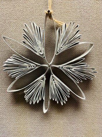 A paper snowflake hangs on a cloth wall.
