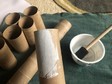 Paper tubes are painted white on the outside and set aside to allow the paint to dry.