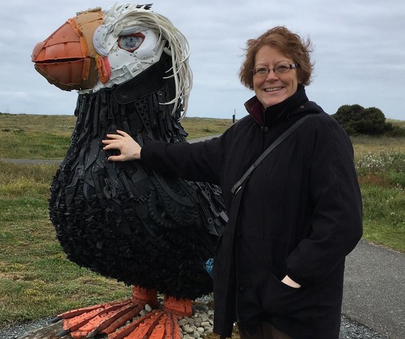 The lead artist and founder of Washed Ashore stands next to a sculpture of a Tufted Puffin.