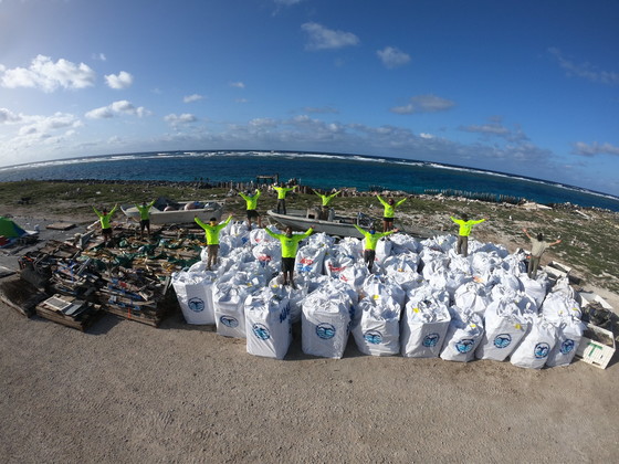 A marine debris removal team stand atop 82,600 pounds of collected marine debris. 