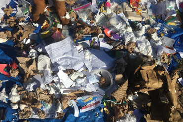 Assorted paper, cardboard, and plastic trash collected from elementary trash bins.