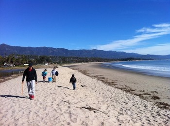 A family walks down the beach collecting debris and gathering data.
