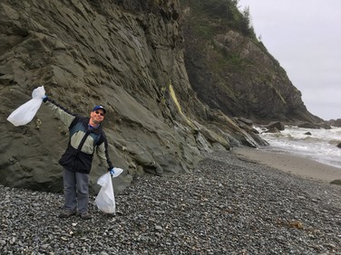 A NOAA team member holds up bags of collected trash from a cleanup. 