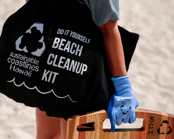 A volunteer holds a DIY beach cleanup kit.