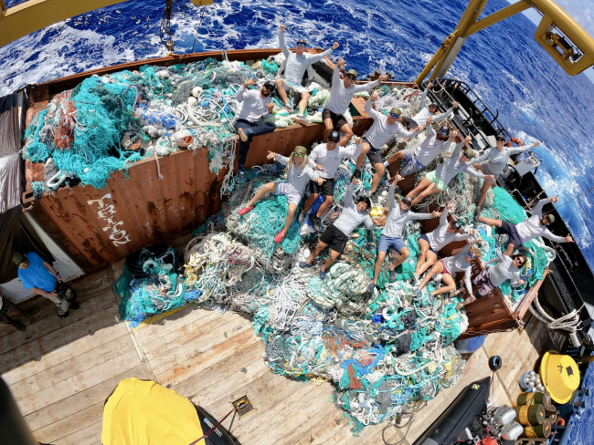 Marine debris team members lay on the 124,000 pounds of marine debris removed during their mission.