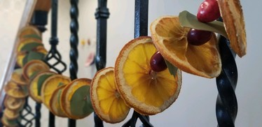 A garland made out of dried oranges, cranberries, and eucalyptus leaves hung on a stairway banister.