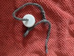 A bottle cap with a hole in the center, with a strand of thick yarn through the string. 