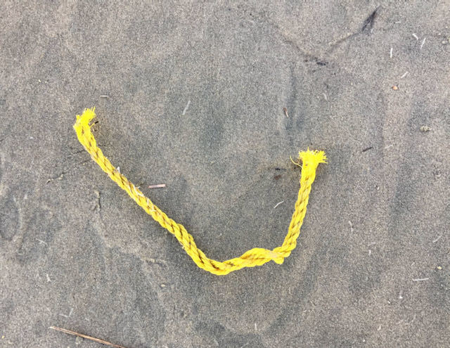 A piece of yellow rope sitting on a beach.