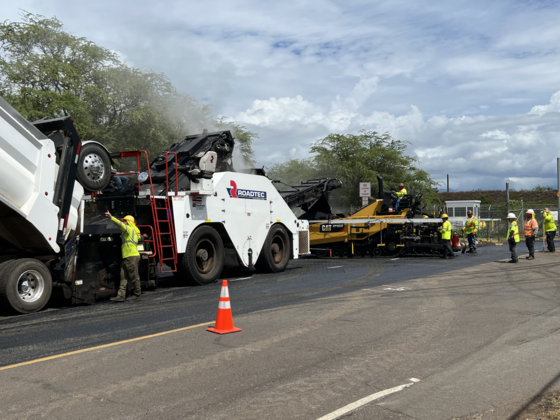 Construction workers repave a pilot roadway using waste plastics in the asphalt.