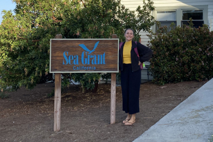Tanya stands next to the California Sea Grant sign in front of the office building.