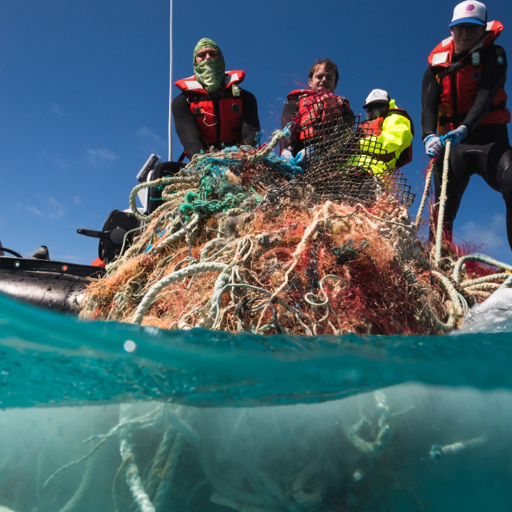People haul a tangle of fishing nets into a boat at Pearl and Hermes Atoll.