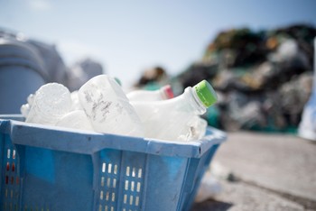 A bin full of empty plastic bottles sitting on a beach.