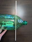 The profile of a two-liter bottle, with a long dowel stick through the bottle near the cap. 