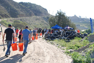 Volunteers walk down to a cleanup site holding buckets and shovels. 