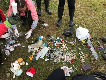 Students sort debris on a grassy field. 