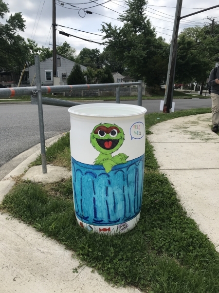 Garbage can decorated with oscar the Grouch. 