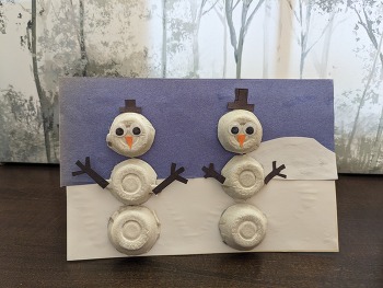 A holiday card featuring two snowmen, made out of upcycled egg cartons.