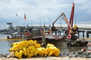 Heavy machinery clearing large marine debris from a waterway.