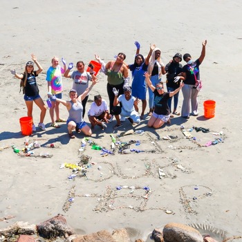 A group of students celebrating a successful cleanup on the beach.