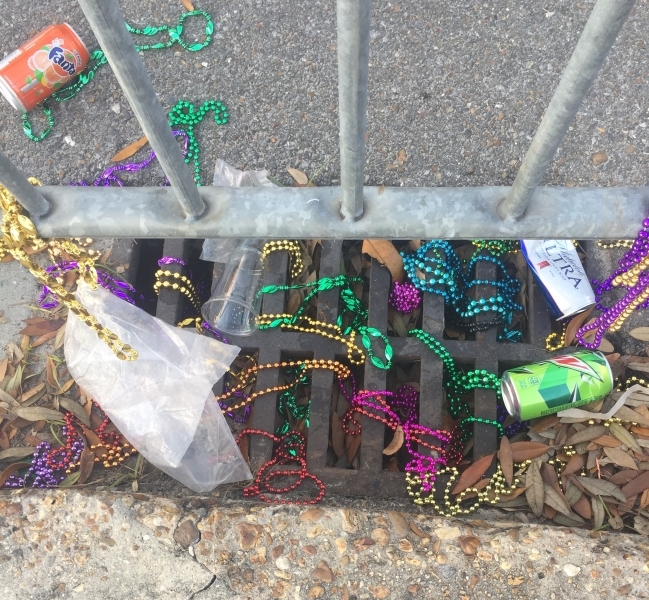 Mardi Gras beads strewn into a storm drain.