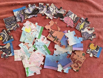 Three different puzzles laid out in pieces on a table.