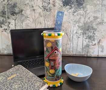 A desk set up with the organizer, a laptop, notebook, and empty crisp bowl.