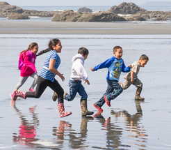 Children running on the beach through shallow water