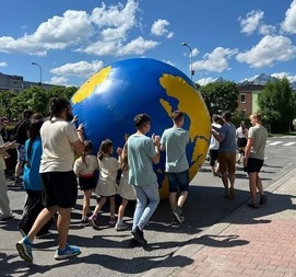 A group pushing a large Globe down the street