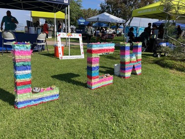 Piñata letters that spell "LCW" on the lawn of a community event. 