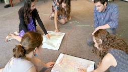 Students sitting on the floor looking at maps