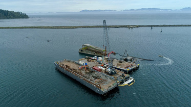 Three barges used to remove an old interstate floating bridge in the middle of a bay.