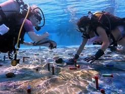 Two scuba divers doing an underwater activity at the bottom of a swimming pool