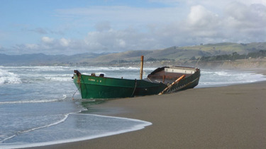 A derelict vessel washed up on a beach.