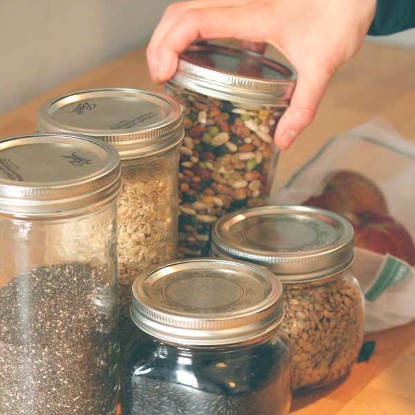 A hand grabbing glass jars filled with dry goods.