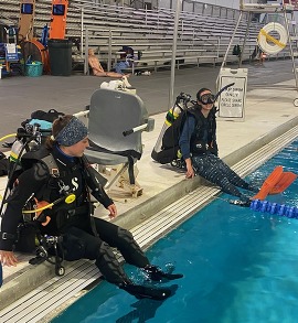 Divers sitting on the edge of a pool.
