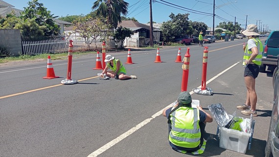 A group of researchers collect road dust from asphalt during a sunny. 