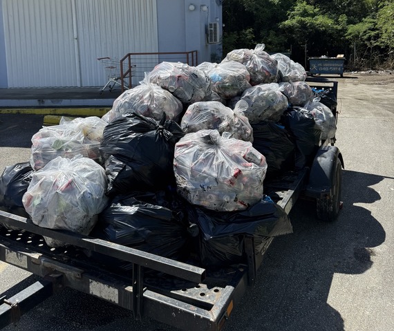 Bags of collected trash piled upon a trailer. 