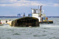 Contractors remove a sunken vessel in a harbor.